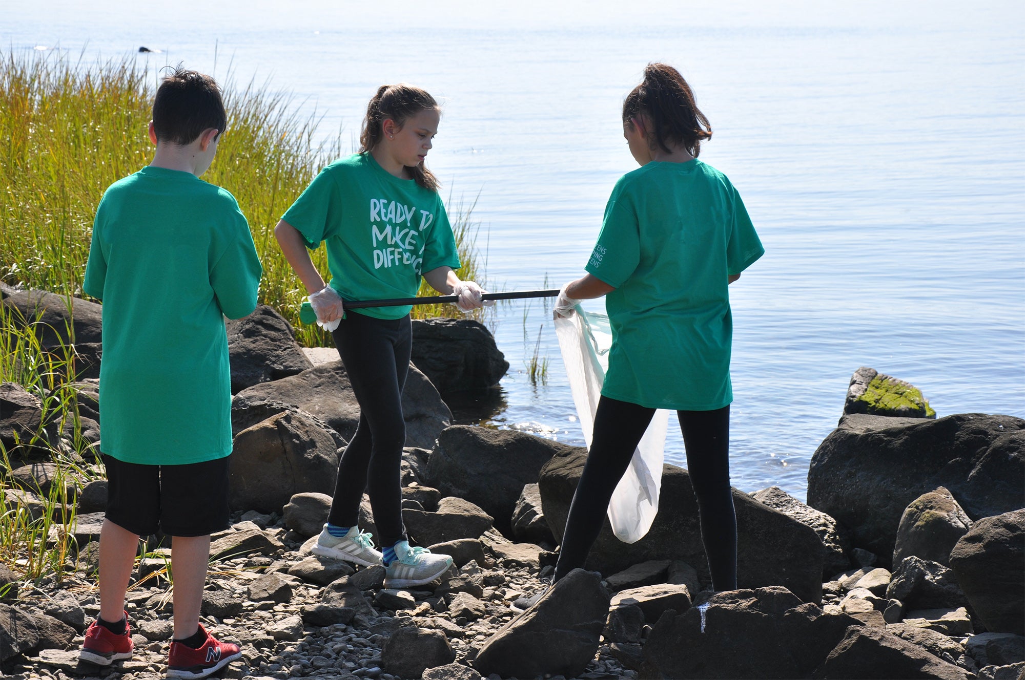 volunteers cleaning up trash along the ocean